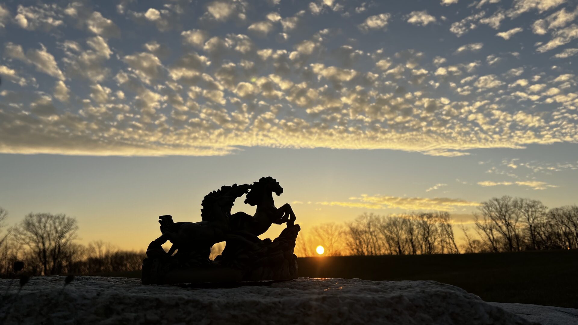 Silhouette of a horse sculpture against a sunset sky